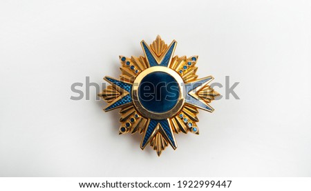 Jewelry on a dark background, yellow metal medal with blue details