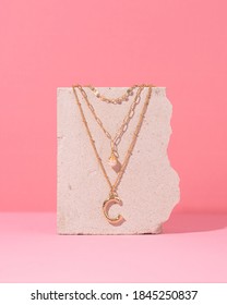 Jewelry on a pink background. Stylish gold rings and necklace with different design on pink background. Product concept for jeweler