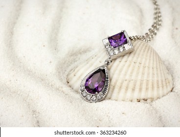 jewelry pendant with gems and diamonds on sand background