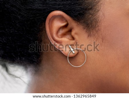jewelry, piercing and people concept - close up of african american woman ear with silver earring