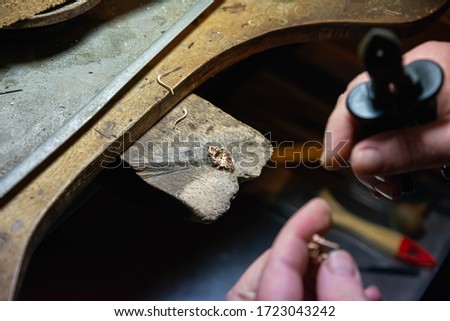 Jewelry processing. Making earrings. Workshop of a jeweler. The jeweler works at his desk, making jewelry