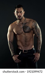 Jewelry for real men. Bearded man with tattooed torso. Macho sexy bare torso. Fit model with tattoo art skin. Sportsman or athlete with beard and hair. Sport and fitness. Masculinity. Muscular torso.