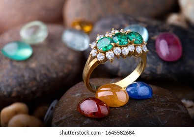 Jewelry ring and round cut mineral gemstones with dark stones background.