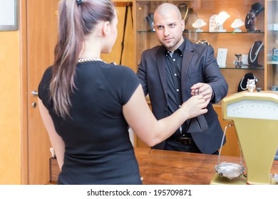 Jewelry Store Owner Is Passing A Sold Product To His Buyer, A Young Woman.