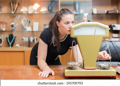 Jewelry Store Owner Weighing Gold Rings And Necklaces To Determine Its Weight And Value.