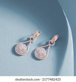  Jewelry theme  Golden earrings and precious stones blue background  Advertising material 