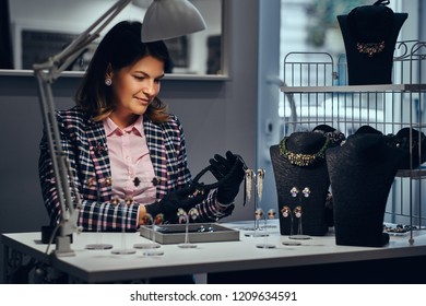 Jewelry Worker Dressed In Elegant Clothes Sitting At Work Table And Make Examine Of Necklace In A Jewelry Store.