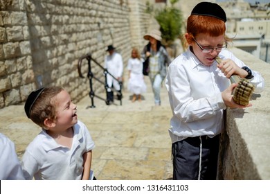 A  Jewish Child Trumpets Into A Shofar - A Jewish Ritual Brass Musical Instrument At The Background Of The Wailing Wall And Old City Of Jerusalem.   Israel. 14 September 2015