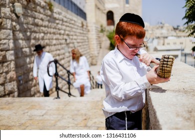 A  Jewish Child Trumpets Into A Shofar - A Jewish Ritual Brass Musical Instrument At The Background Of The Wailing Wall And Old City Of Jerusalem.   Israel. 14 September 2015