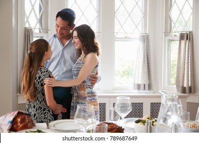 Jewish couple and daughter embracing before Shabbat meal