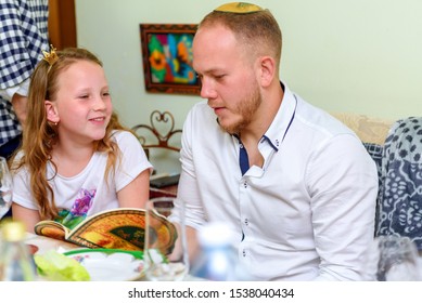 Jewish Family Celebrate Passover Seder Reading The Haggadah.