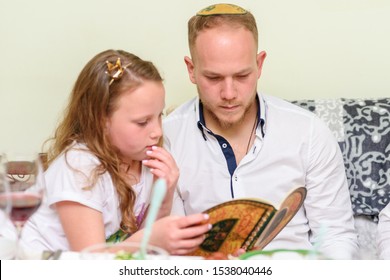 Jewish Family Celebrate Passover Seder Reading The Haggadah.