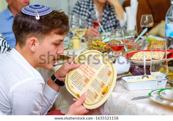Jewish
family celebrate Passover Seder reading the Haggadah. Young jewish
boy with kippah reads the Passover
Haggadah.