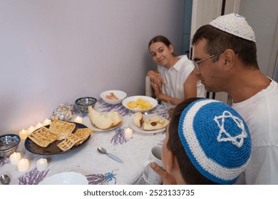  jewish family celebrating hanukkah, israel, boy in kippah, jewish holidays, yom kippur feast, table with food, honey, donuts, family holiday, religious family, family praying, Jewish woman - Powered by Shutterstock