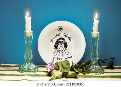 Jewish greetings Shabbat Shalom. A plate with the inscription Shabbat Shalom and two burning candles on the table. - Shutterstock ID 2211818063
