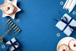 Jewish Holiday Hanukkah Concept. Frame Of Traditional Jelly Donuts, Menorah, Candles And Gift Boxes On Blue Background. Flat Lay, Top View.

