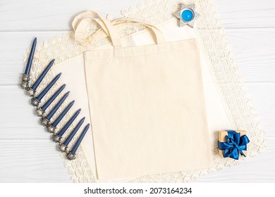 Jewish Holiday Hanukkah Concept With Tote Bag Mockup, Menorah And Gift Box Over White Background