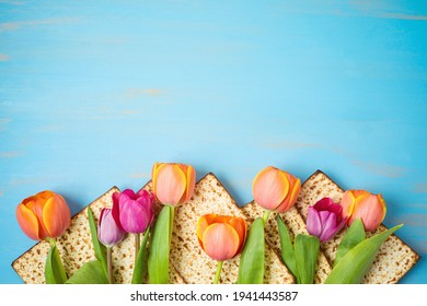 Jewish holiday Passover celebration concept with matzah and tulip flowers on wooden table. Pesach background