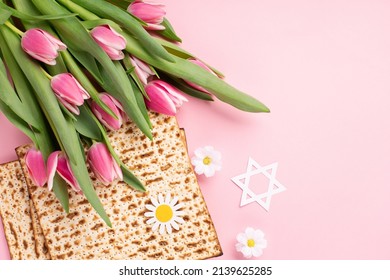 Jewish Holiday Passover Greeting Card Concept With Matzah, Nuts, Tulip And Daisy Flowers On Pink Table. Seder Pesach Spring Holiday Background, Top View, Copy Space.