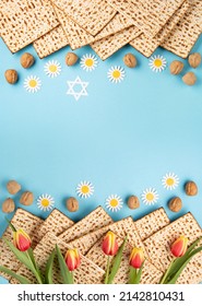 Jewish Holiday Passover Greeting Card Concept With Matzah, Nuts, Tulip And Daisy Flowers On Blue Table. Seder Pesach Spring Holiday Background, Top View, Copy Space.