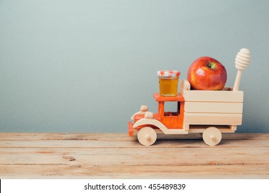 Jewish Holiday Rosh Hashana Background With Toy Truck, Honey And Apples On Wooden Table