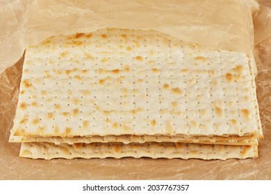 Jewish Kosher Matzah For The Religious Holiday Of Passover On A Wooden Table Wrapped In A Yellow Sheet Of Paper