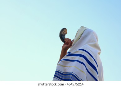 Jewish man blowing the Shofar (horn) of Rosh Hashanah (New Year). Religious symbol.

