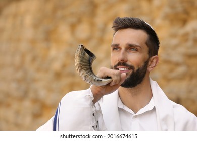 Jewish Man In Kippah And Tallit Blowing Shofar Outdoors. Rosh Hashanah Celebration