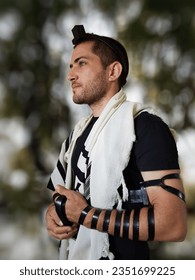 A jewish man pray in the forest with Tallit and Tefillin.