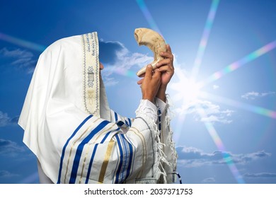Jewish man Rabbi in tallit blowing the Shofar of Rosh Hashanah (New Year) on sunset time. Blowing the shofar for the Feast of Trumpets, jew in traditional tallith prayer shawl blowing the ram's horn