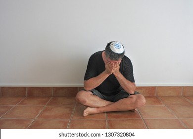 Jewish Man Sitting On The Ground In His Home During Shiva, The Week-long Mourning Period In Judaism For First-degree Relatives That Passed Away.