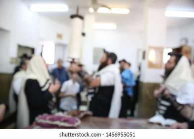 Jewish Men In Synagogue Praying, While Holding Up A Torah Scroll, Blurred