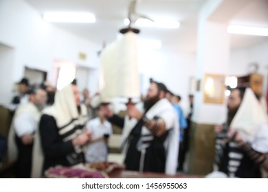 Jewish Men In Synagogue Praying, While Holding Up A Torah Scroll, Blurred