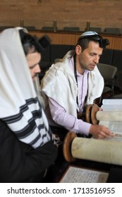 Jewish Rabbi Men Reading And Praying From A Torah Scroll In A Synagogue On Jewish Holiday. 