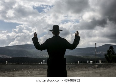 Jewish raising his hands to heaven and pray to God.
Background of bright blue sky with clouds