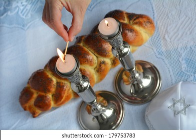 Jewish Woman Hand Lit Shabbat Candles With Uncovered Challah Bread And Kippah On Sabbath Eve Table. 