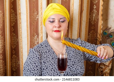 A Jewish Woman In A Kisui Rosh Headdress Extinguishes The Avdala Candle In A Glass Of Wine After Shabbat.. Horizontal Photo