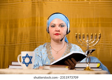 A Jewish woman in a kisui rosh headdress, a Torah teacher in headphones with a microphone, tells women which books to study the commandments. Horizontal photo. - Shutterstock ID 2311973709