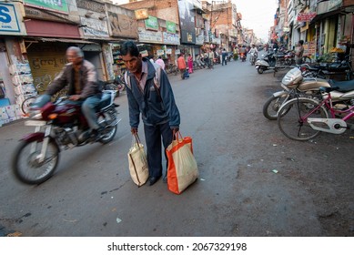 Jhansi; Uttar Pradesh, India-Feb 16 2012: Man Carrying Heavy Bag Full Of Household Things, Keeping On Street While Walking.