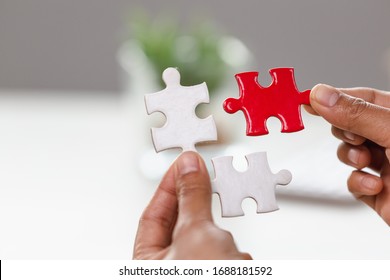 Jigsaw connection between white and red jigsaw puzzles, Jigsaw puzzle in the hand of a businessman,  Business team assembling Jigsaw puzzle.