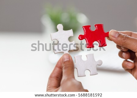 Jigsaw connection between white and red jigsaw puzzles, Jigsaw puzzle in the hand of a businessman,  Business team assembling Jigsaw puzzle.