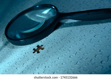 Jigsaw puzzle with missing piece and an investigator's magnifying glass in blue ambient hue. - Shutterstock ID 1745132666