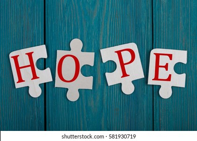 Jigsaw Puzzle Pieces with text "HOPE" on blue wooden background