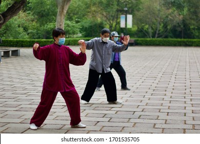 Jinan Shandong CHINA, April 10th, 2020: Chinese Practicing Tai Chi In A Chinese Park Wearing Mask