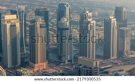 JLT skyscrapers near Sheikh Zayed Road aerial timelapse. Residential buildings and villas behind. Hazy weather