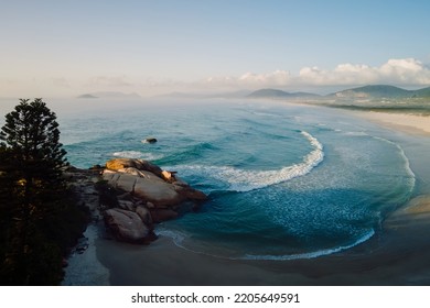 Joaquina Beach With Rocks And Ocean Waves At Sunrise In Brazil. Aerial View