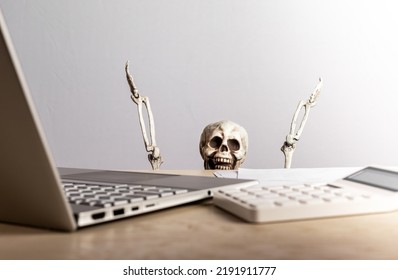 Job Burnout. Skeleton Peeking Out From Desk With Laptop And Calculator. Computer Geek. Emotional And Physical Exhaustion, Frustration, Stress From Work Overload, Deadlines. High Quality Photo