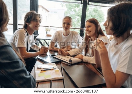 Job with documents in progress, start up. Group of young friends are in the cafe restaurant.