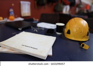 Job Hazard Analysis Risk Assessment Book Placing On The Table With Yellow Hard Hat Computer At The Back Ground  