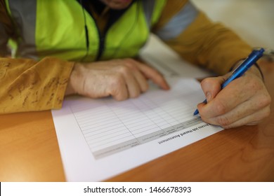 Job hazard Assessment (JHA) work permit paper document work on the table with defocused male hand writing with blue pen at the background construction site Perth